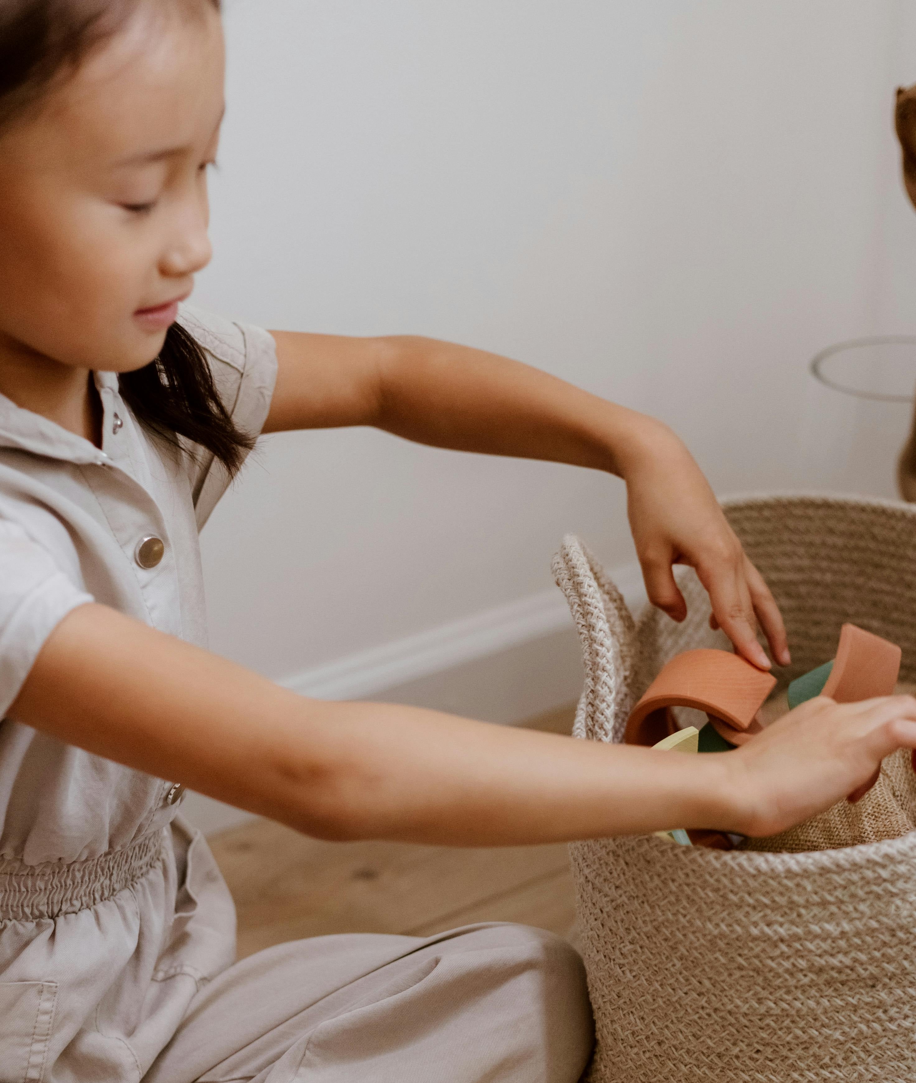 Asian American Girl putting toys in a basket