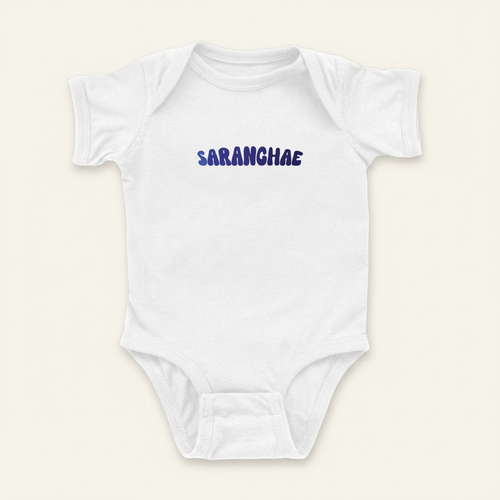 Saranghae Onesie flat lay on clean warm ivory background, zero shadows — CULTR editorial product photo